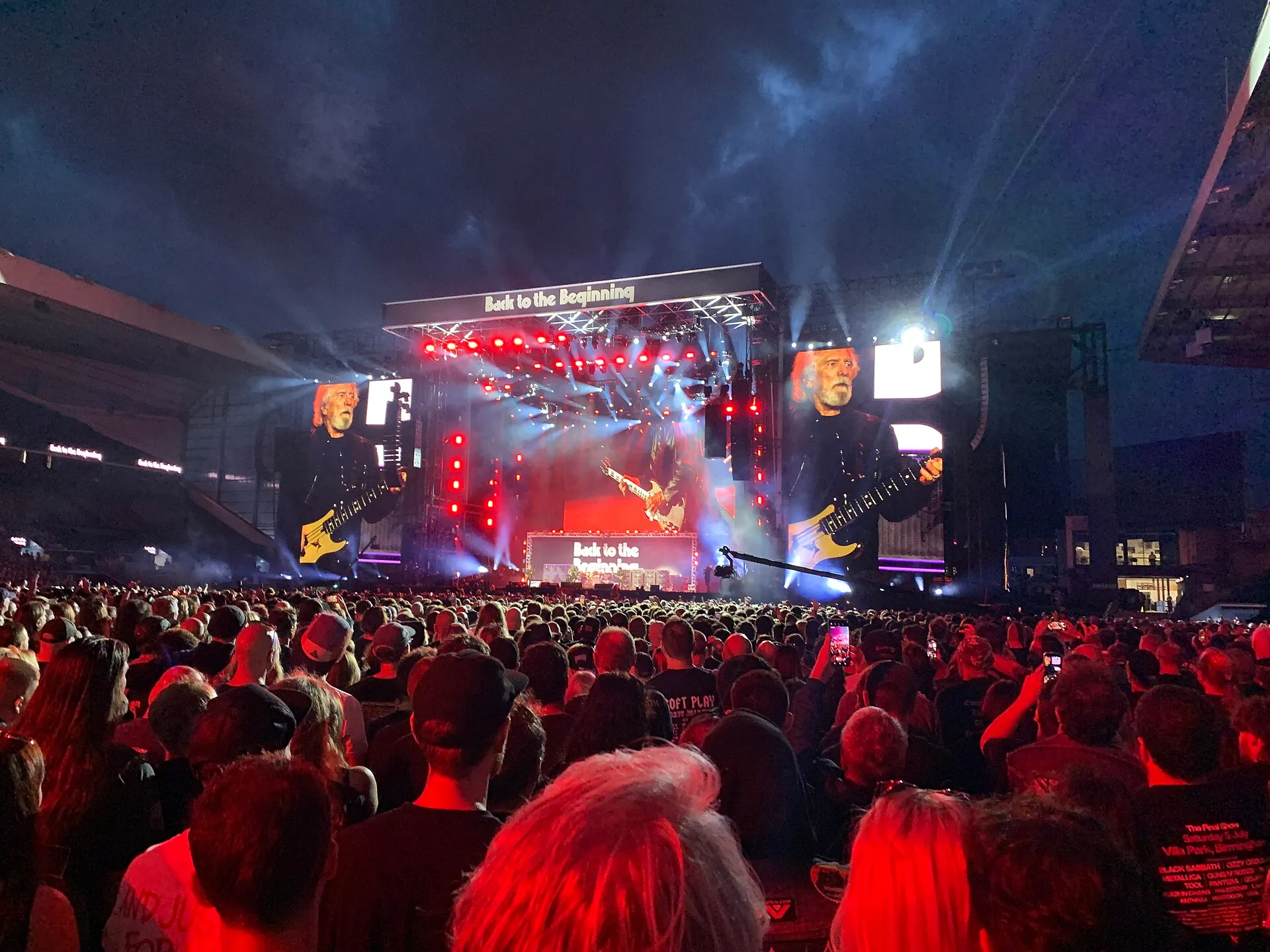 Black Sabbath’s four original members perform together on a large stage in Birmingham in July 2025, seen from behind the audience.
