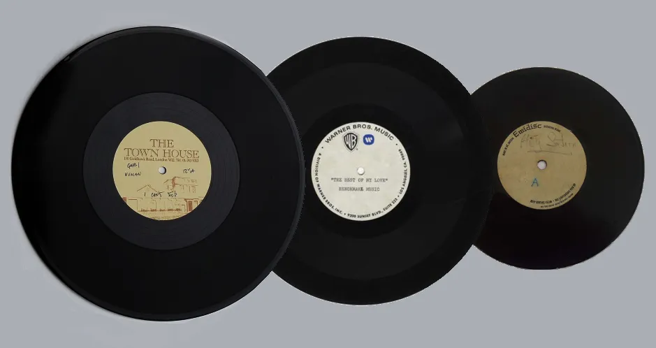 Several black lacquer and acetate recording discs of different diameters arranged together on a light surface.