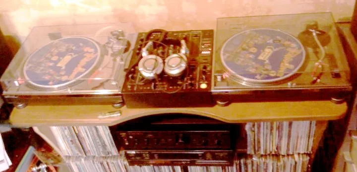 Two silver Technics turntables positioned on either side of a black DJ mixer.