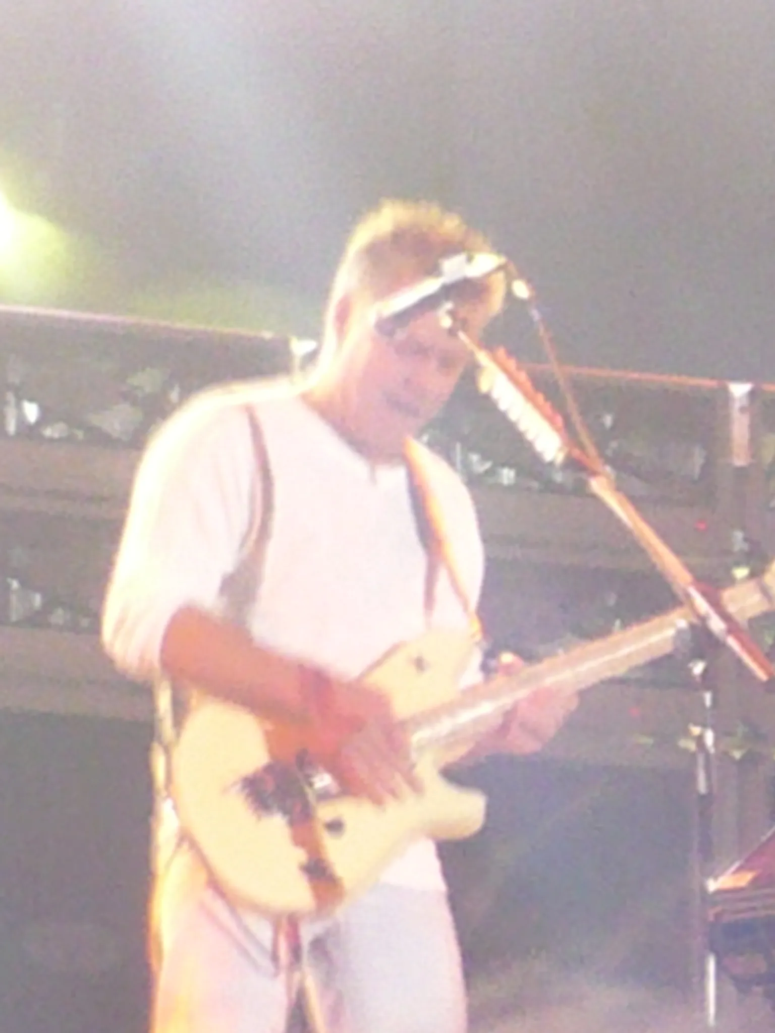 Eddie Van Halen performs onstage in Quebec City in 2008, holding a striped electric guitar beneath red concert lights.