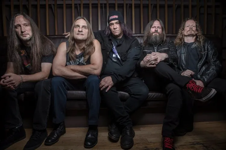 Five members of the Bay Area thrash band Exodus pose together outdoors in a 2014 group photograph.