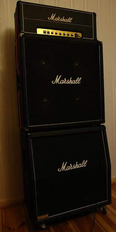 A black Marshall amplifier head sits on two stacked speaker cabinets, the upper cabinet angled and the lower cabinet straight.