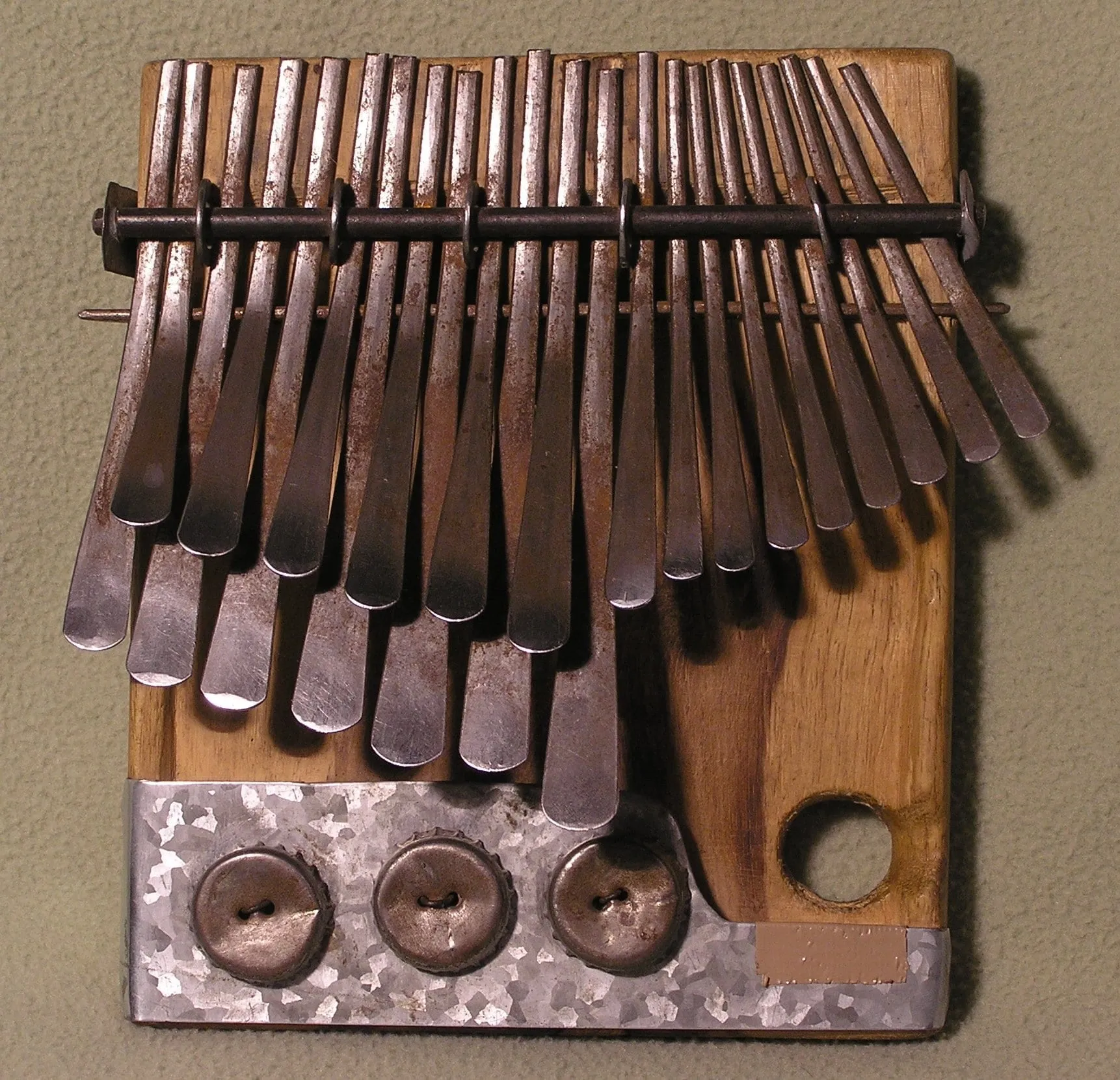 A close view shows staggered rows of broad metal keys attached to the dark wooden soundboard of a mbira dza vadzimu.