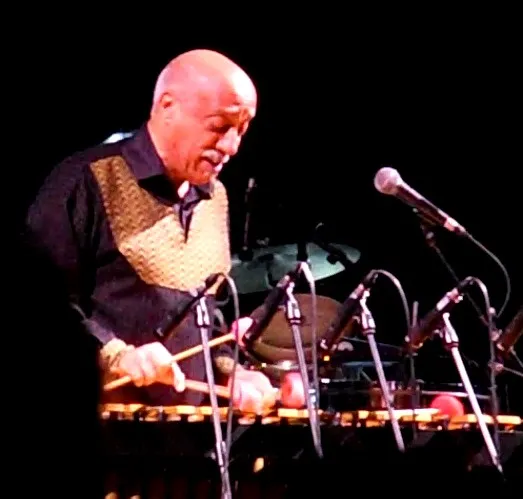 Mulatu Astatke leans toward his vibraphone during a 2013 festival performance, holding two mallets above the bars.