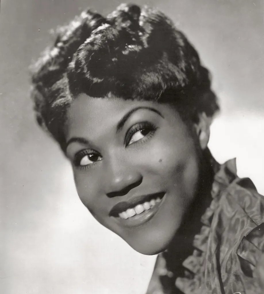 Black-and-white head-and-shoulders publicity portrait of Sister Rosetta Tharpe smiling toward the camera in 1938.