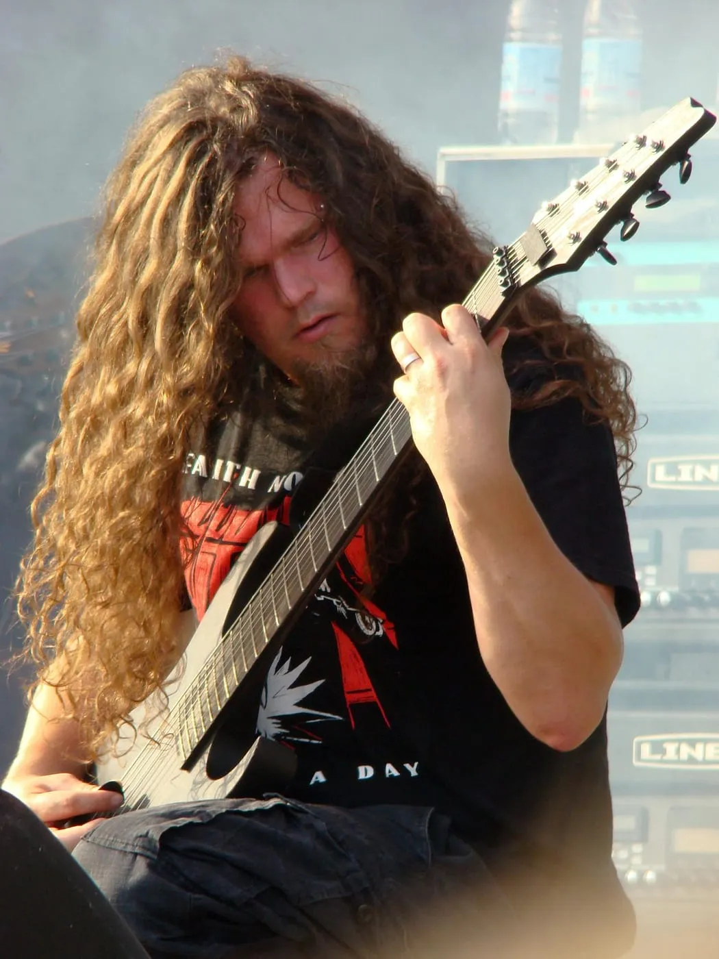Marten Hagstrom leaning over his extended-range guitar during a brightly lit Meshuggah concert.