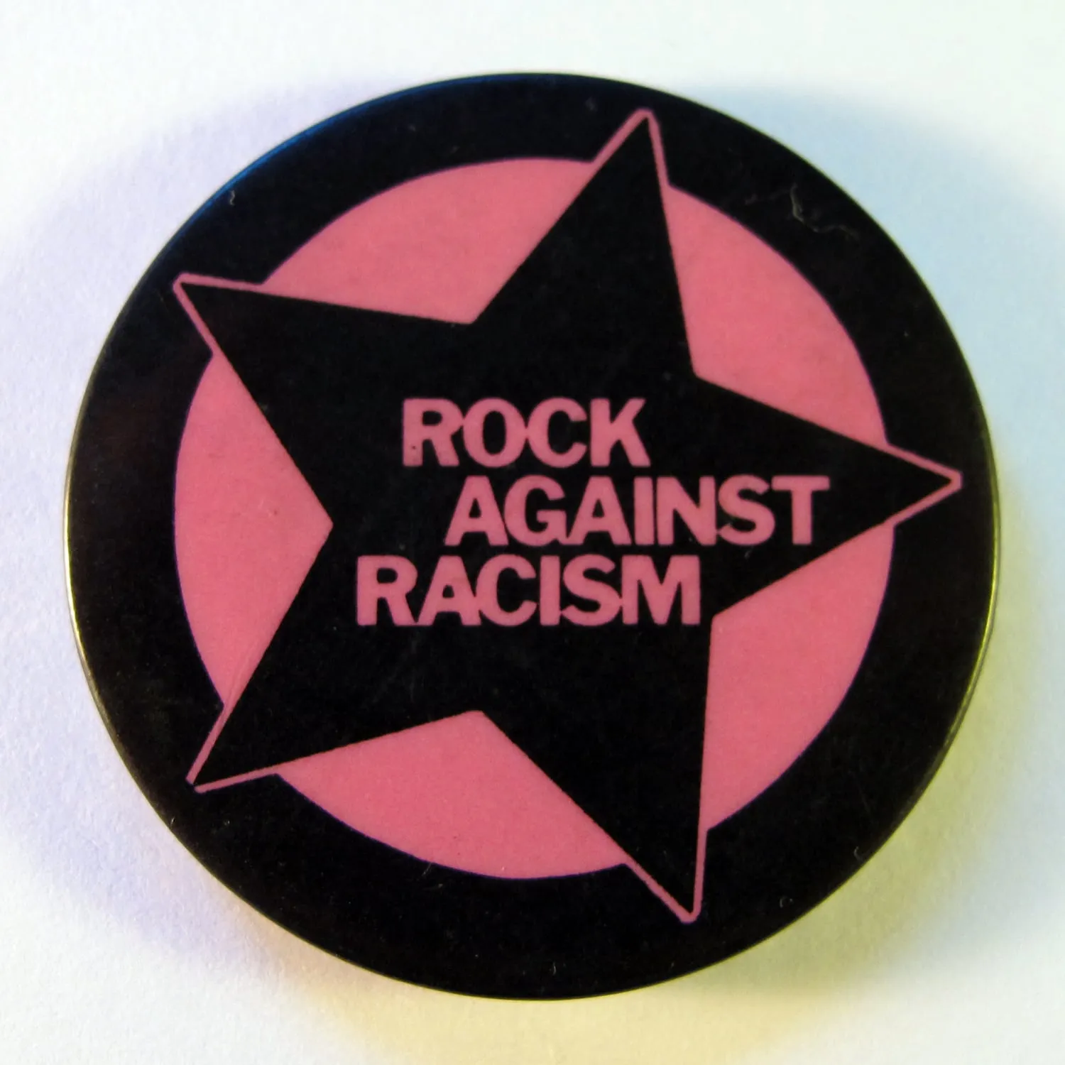 A circular Rock Against Racism badge design reading Love Music Hate Racism in black, white, and red.