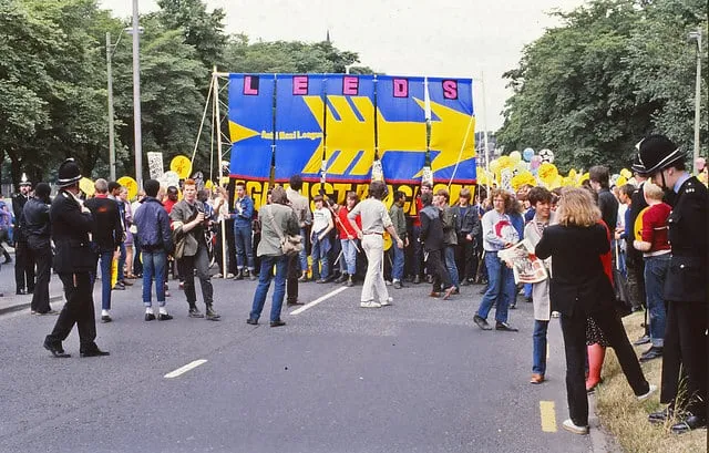 Rock Against Racism marchers moving through Leeds in July 1981 with banners raised above the street.