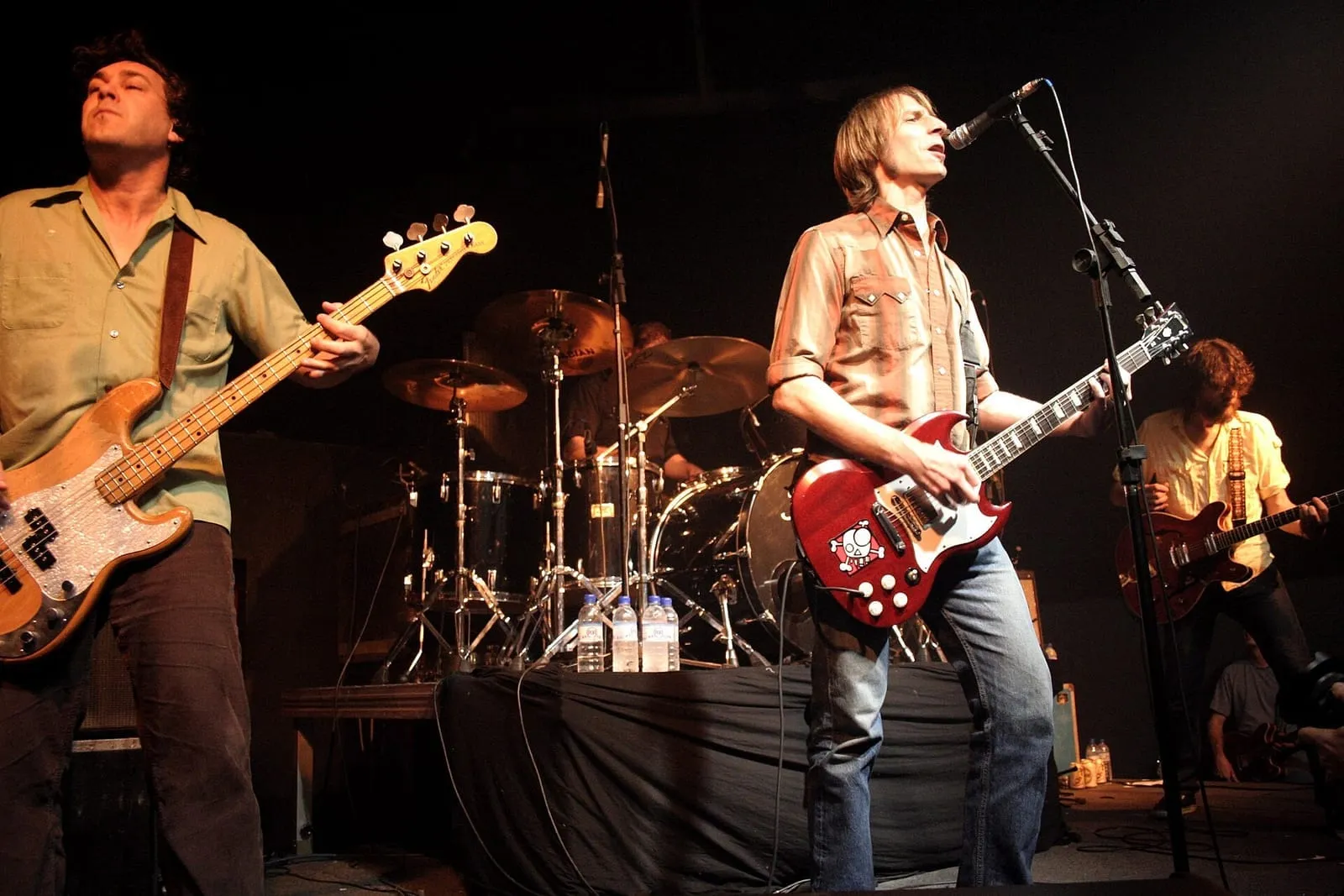 Mudhoney performing under red and amber stage lighting during a concert in 2007.