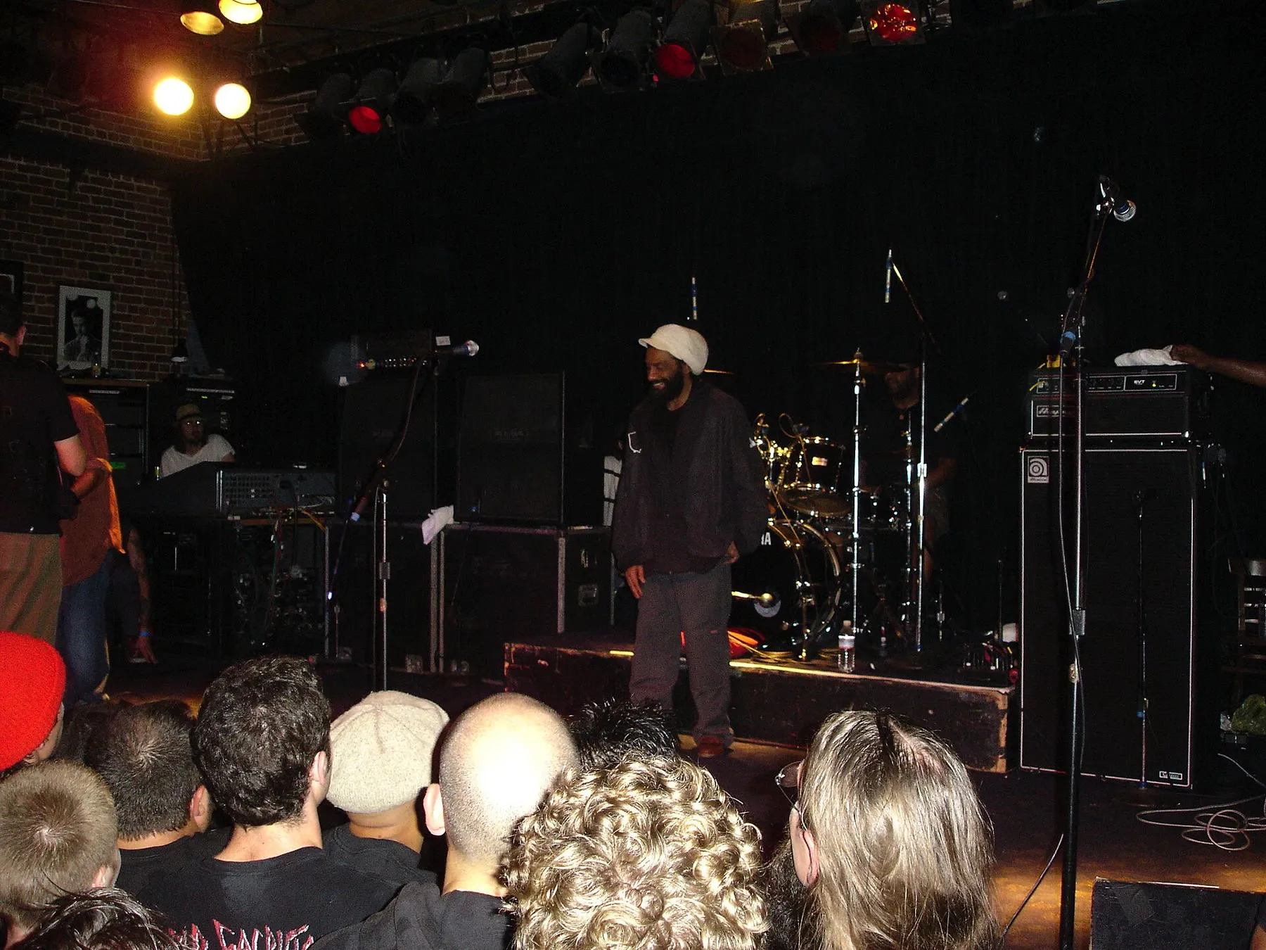 Bad Brains playing live, with vocalist H.R. leaning forward under warm stage lighting.