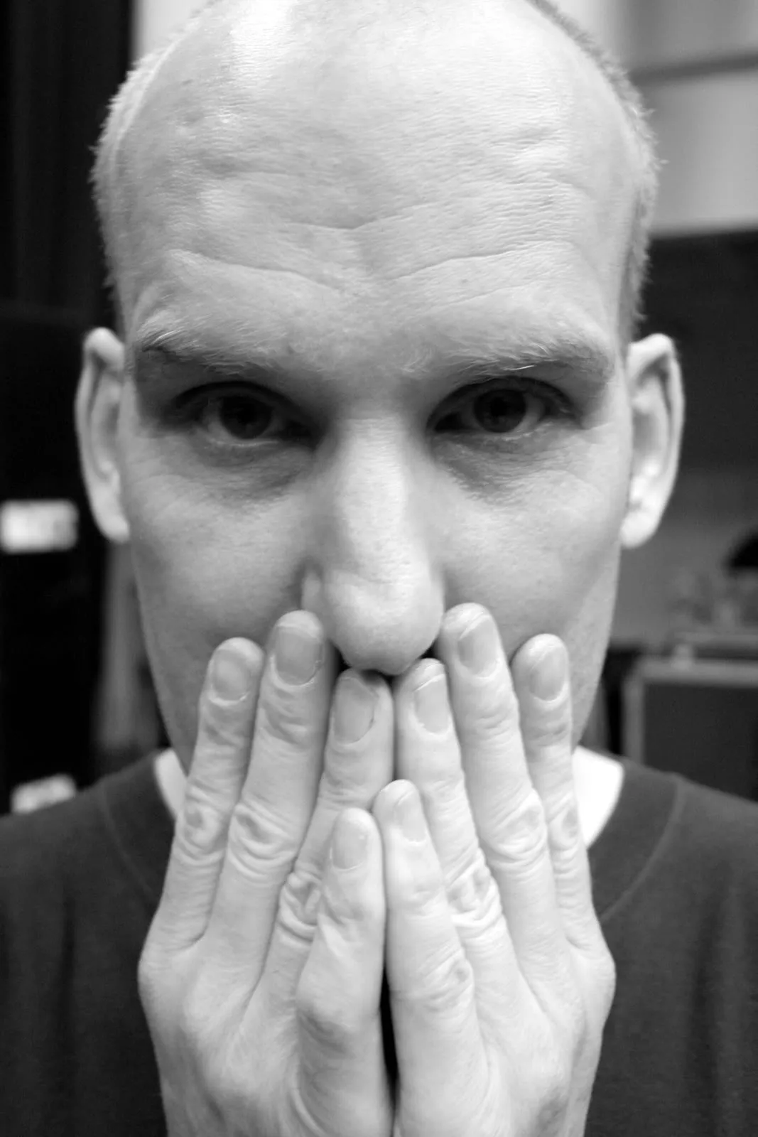 Ian MacKaye singing into a microphone while playing a baritone guitar onstage.
